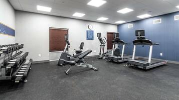 A gym with treadmills, elliptical machines, and weight benches.