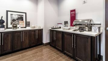 A modern kitchen with dark wood cabinets, a white countertop, and a coffee station.