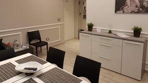 A modern kitchen with white cabinetry, a dining area with a table and chairs, and a painting on the wall.
