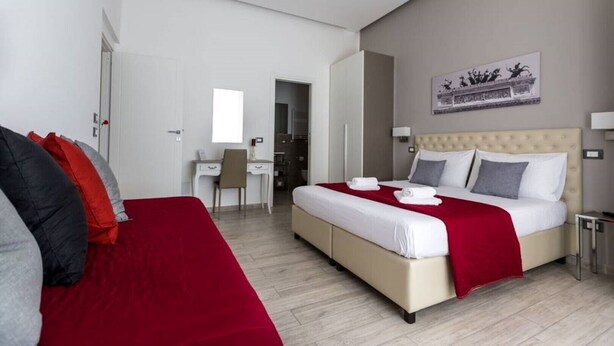 A modern hotel room with a large bed, a desk, and a chair.