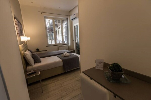 A small, cozy bedroom with a bed, bedside table, and a potted plant.