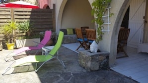 An outdoor patio with stone flooring, colorful chairs, and a wooden fence.