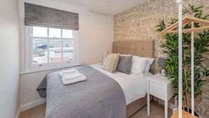 Un dormitorio con una cama grande, un ventanal con vistas, una pared con estampados de animales y una planta colgante.