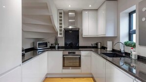 Una cocina moderna con armarios blancos, electrodomésticos de acero inoxidable y piso de madera.