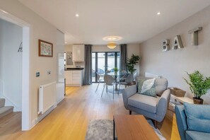 A modern living room with a sofa, a coffee table, and a dining area with a table and chairs. - Fantastic 3-bed house in Bath with free parking (BATH)