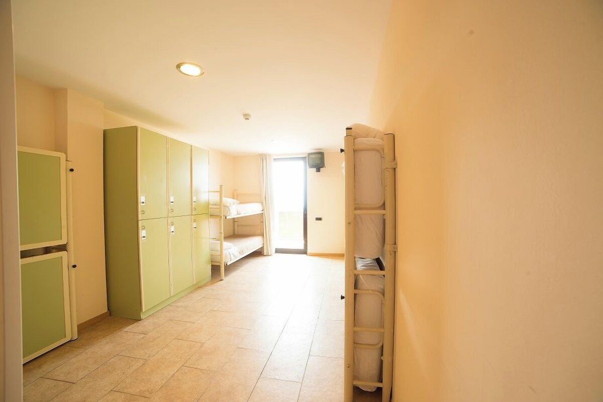 A hotel room with bunk beds, a wardrobe, and a bedside table.
