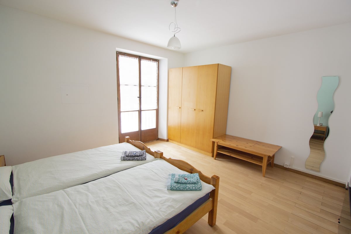 Een slaapkamer met twee bedden, een garderobe, een bankje en een spiegel.
