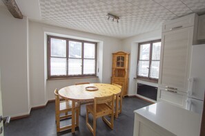 A kitchen with a round wooden table, wooden chairs, a wooden cabinet, and a refrigerator. - Chalet Cuore delle Alpi (Airolo)