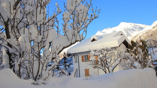 Una casa cubierta de nieve con una montaña al fondo.