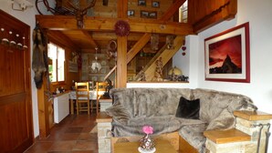 Ein gemütliches Wohnzimmer mit Holzbalkendecke, Kamin aus Stein und einem gerahmten Bild an der Wand.