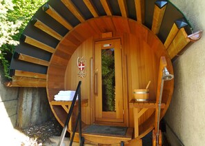 A wooden sauna with a circular design, a door, a towel rack, a bucket, and a towel. - apartment/ flat - Passy (Passy)