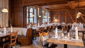 Un restaurante con interiores de madera, varias mesas dispuestas para comer y lámparas colgantes.