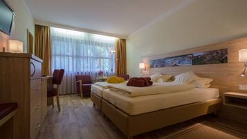 Ein Hotelzimmer mit Bett, Schreibtisch, Stuhl, Fernseher und einem Fenster mit Vorhängen.