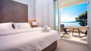 Ein Hotelzimmer mit einem großen Bett, einem Balkon mit Tisch und Stühlen sowie Meerblick.