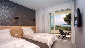Ein modernes Hotelzimmer mit zwei Betten, einem Balkon mit einem Stuhl und Meerblick.