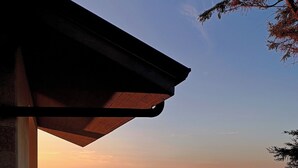 Un balcón con vista al mar, una zona pavimentada y una calle con valla.