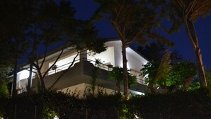 Un edificio moderno con techo plano y ventanas amplias, rodeado de árboles.