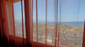 Una ventana con vistas a un paisaje costero, que incluye edificios y vegetación.