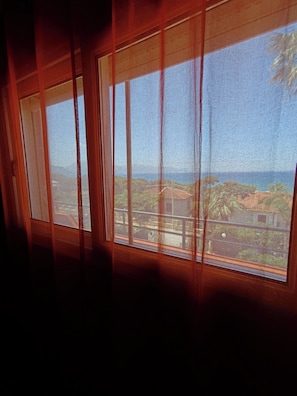 A window with a view of a coastal landscape, including buildings and vegetation.