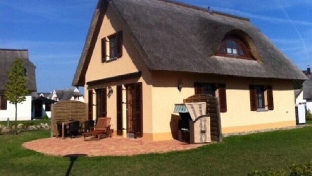 A traditional house with a steeply pitched thatched roof, a small porch with a wooden bench, and a brick pathway leading to the entrance. - Vacation home close to the beach with sauna incl. additional costs, home office possible (Glowe)