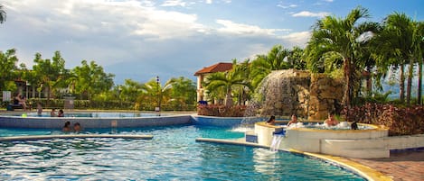 Una piscina al aire libre, sombrillas, sillones reclinables de piscina