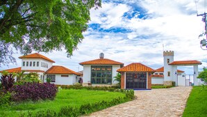 A building with multiple red-tiled roofs and white walls, a stone pathway leading to the entrance, and lush green landscaping. - Casa Bohemia (Campoalegre)