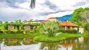 A serene lakeside setting with a small island, lush greenery, and traditional buildings with red-tiled roofs. - Casa Bohemia (Campoalegre)