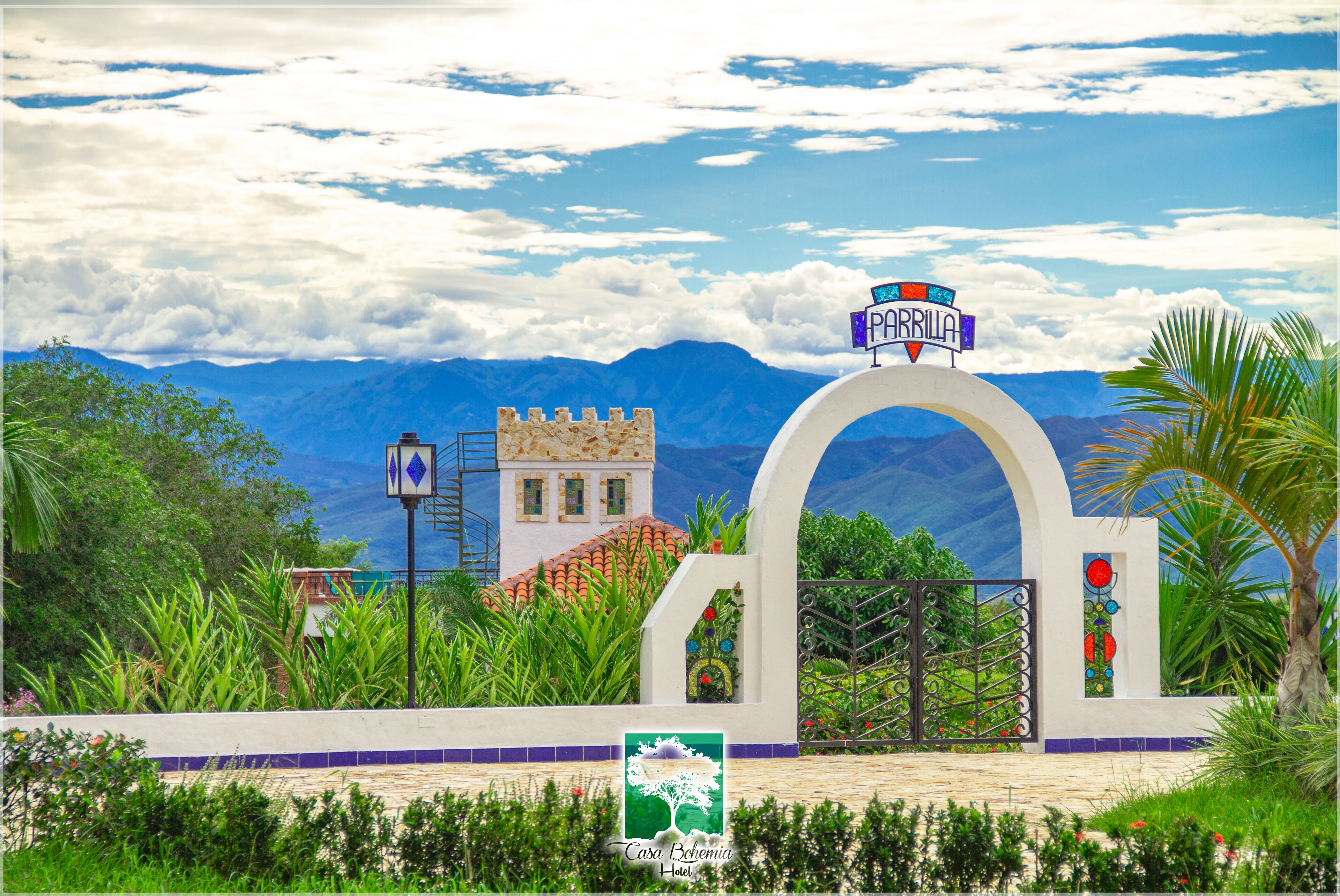 Entrada de hotel con un cartel que dice "PARRILLA" y vistas de montañas al fondo.