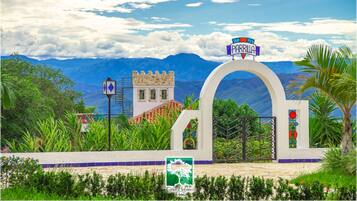 Entrada de hotel con un cartel que dice "PARRILLA" y vistas de montañas al fondo.