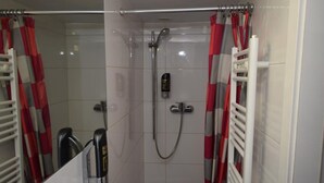 Un baño con ducha, inodoro y espejo.
