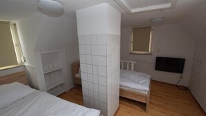 Un dormitorio con dos camas, televisión y ventana.