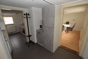 A compact kitchen with grey cabinets, a black stand, and a dining area with a table and chairs. - AB Apartment 27 (Stuttgart)