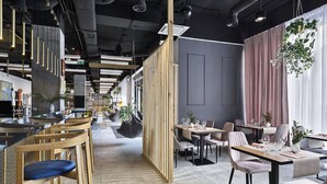 Un interior de restaurante moderno con techos altos, conductos expuestos y una combinación de asientos de madera y tapizados.
