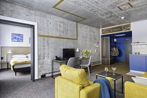 Una habitación de hotel moderna con cama, escritorio, sofá y kitchenette.