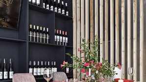 Un comedor moderno con una mesa larga, sillas acolchadas y una vinoteca al fondo.