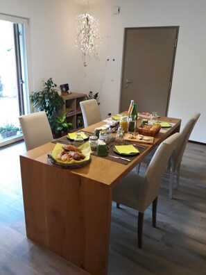A dining area with a wooden table set for breakfast, including croissants and juice. There are chairs around the table, and a plant is visible in the background. - Masetto Egidio Agritur (Castel Ivano)