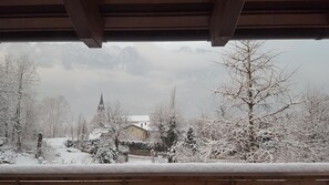 A snowy landscape with a church and buildings, viewed from a covered balcony. - Masetto Egidio Agritur (Castel Ivano)