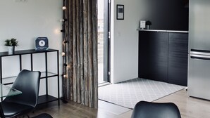 Quarto de hotel moderno com área de jantar, cozinha e uma janela grande.