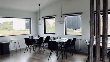 Un comedor moderno con ventanas amplias, sillas negras y una mesa blanca.