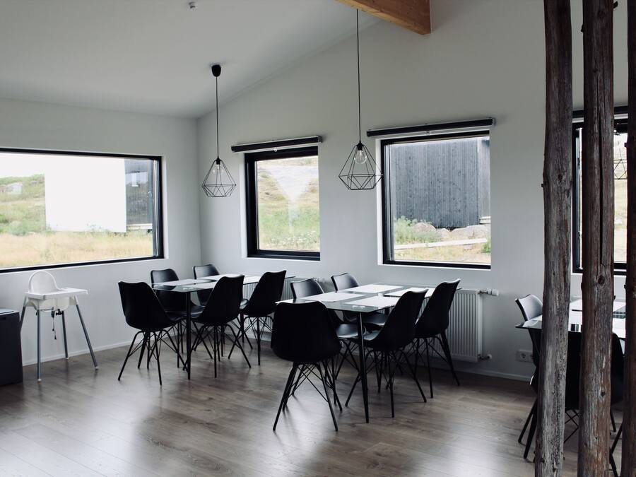Un comedor moderno con ventanas amplias, sillas negras y una mesa blanca.