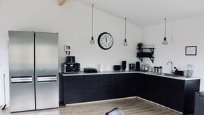 Cozinha moderna com bancada preta, eletrodomésticos de aço inoxidável e iluminação pendente.