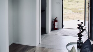 Um interior moderno com piso de madeira, uma cadeira suspensa preta, um sofá preto e vista para área externa através de uma porta de vidro.