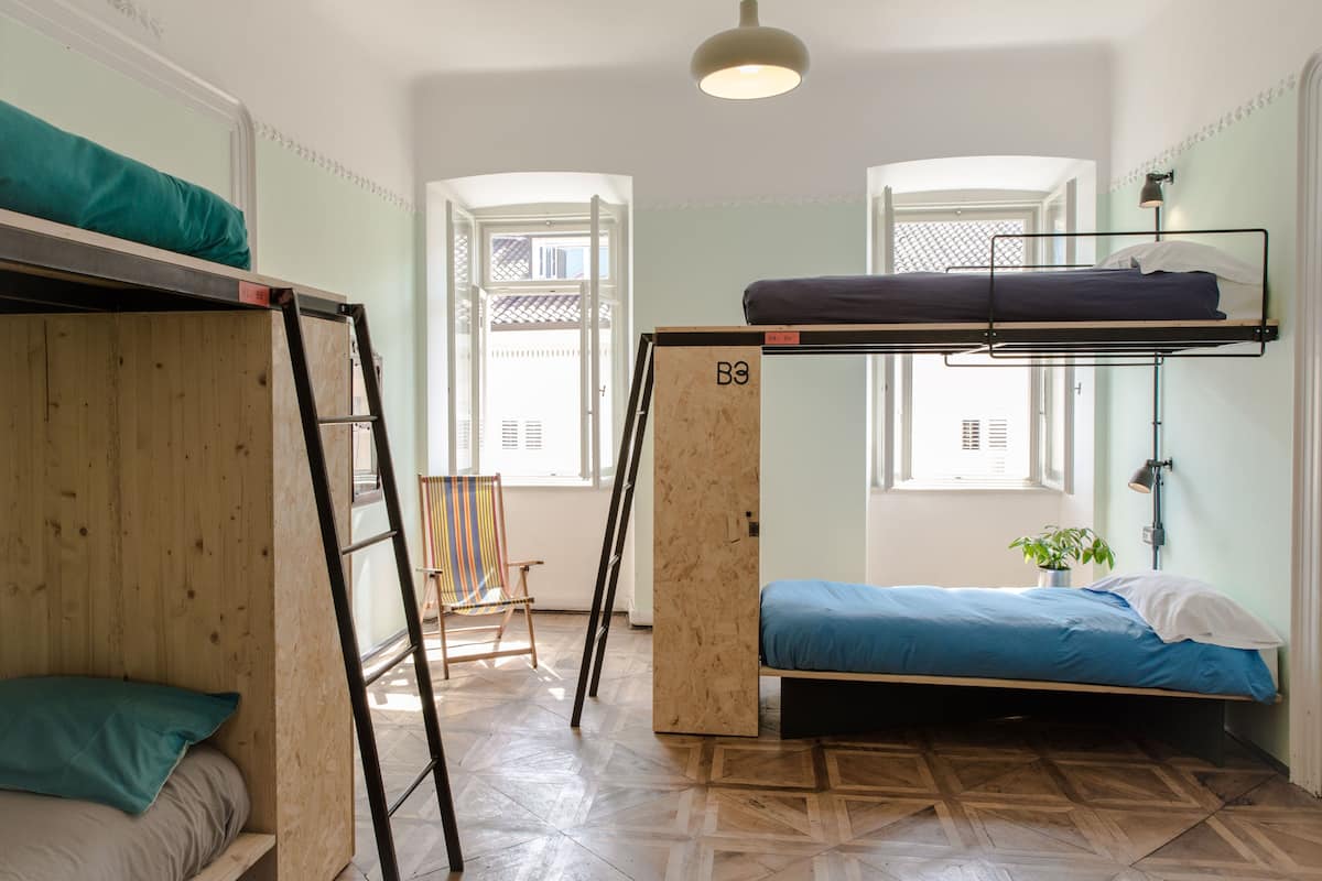 Un dormitorio con literas, una escalera, una silla y una planta en maceta.