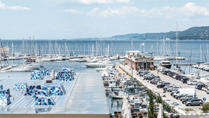 Un puerto deportivo con numerosas embarcaciones amarradas, un estacionamiento con coches y un edificio con un cartel que dice "MARINA RIO GUSTO".