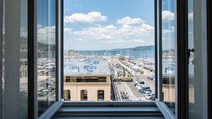 Vista desde una ventana sobre un puerto deportivo con barcos, una carretera y edificios.