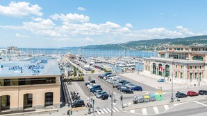 A marina with boats, a parking area, and a building with a sign. - ControVento (Trieste)