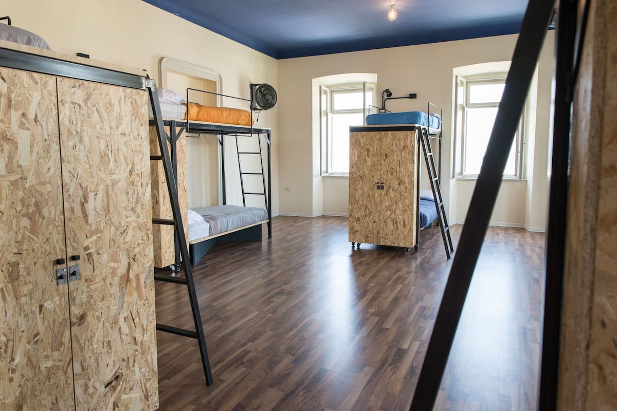 Una habitación con dos literas, un armario de madera y una escalera.