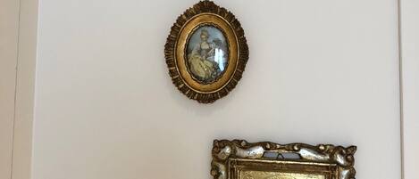 Tres cuadros decorativos con marcos dorados, sujetos a la pared, que representan escenas clásicas.