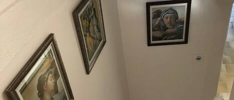 A staircase with white walls and three framed artworks.