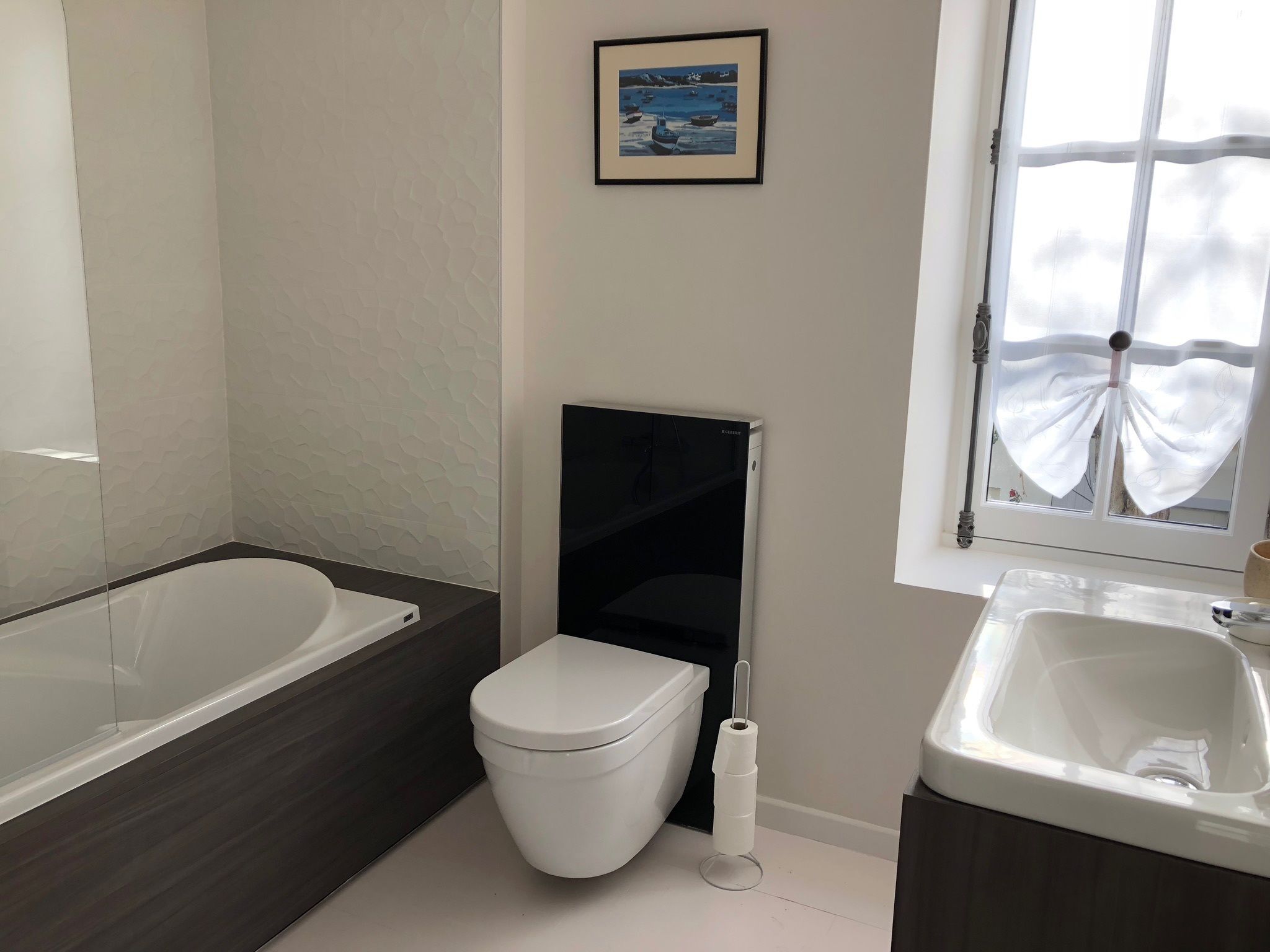 Un baño con bañera, inodoro, lavabo y una ventana con cortinas.